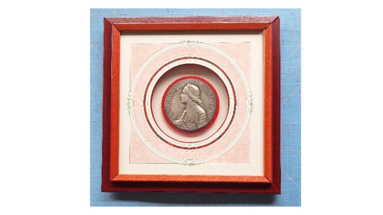 Encadrement d'une médaille "Bienheureuse Jeanne d-Arc". Lavis à l''ancienne avec motifs florales dessinés, double filets en rond, médaille en boitage rehaussée sur cercle en velours rouge