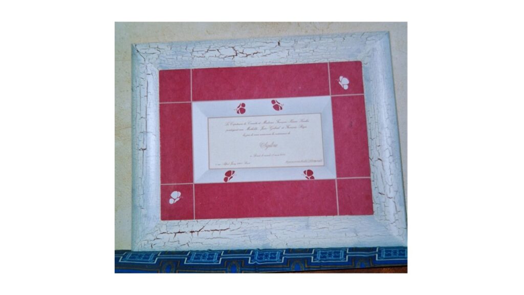 Encadrement baguette bois , passe partout habillé d'un papier rouge et motifs découpés se retrouvant sur le biseau lolo